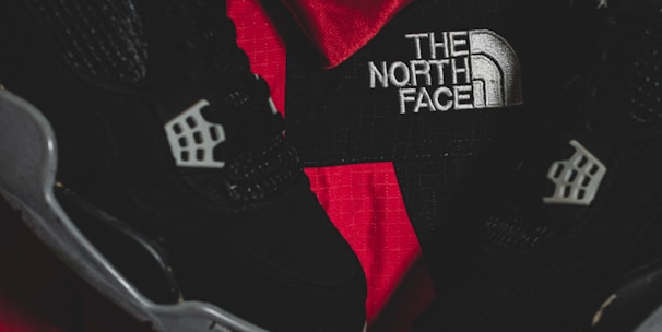 Black athletic shoes are placed alongside red and black sportswear bearing logos from Spalding and The North Face.