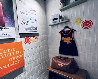 A small retro-themed display with a focus on athletic apparel and shoes. The walls feature a series of posters showcasing various Nike shoes from different years. A black gym tank top and a brown leather gym bag are prominently positioned on a wooden bench. There are decorative elements like potted plants on wall-mounted shelves and smiley face icons. The environment has a nostalgic and sporty atmosphere.